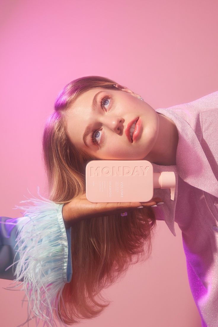 Model with a pink Monday beauty bottle against a pink background
