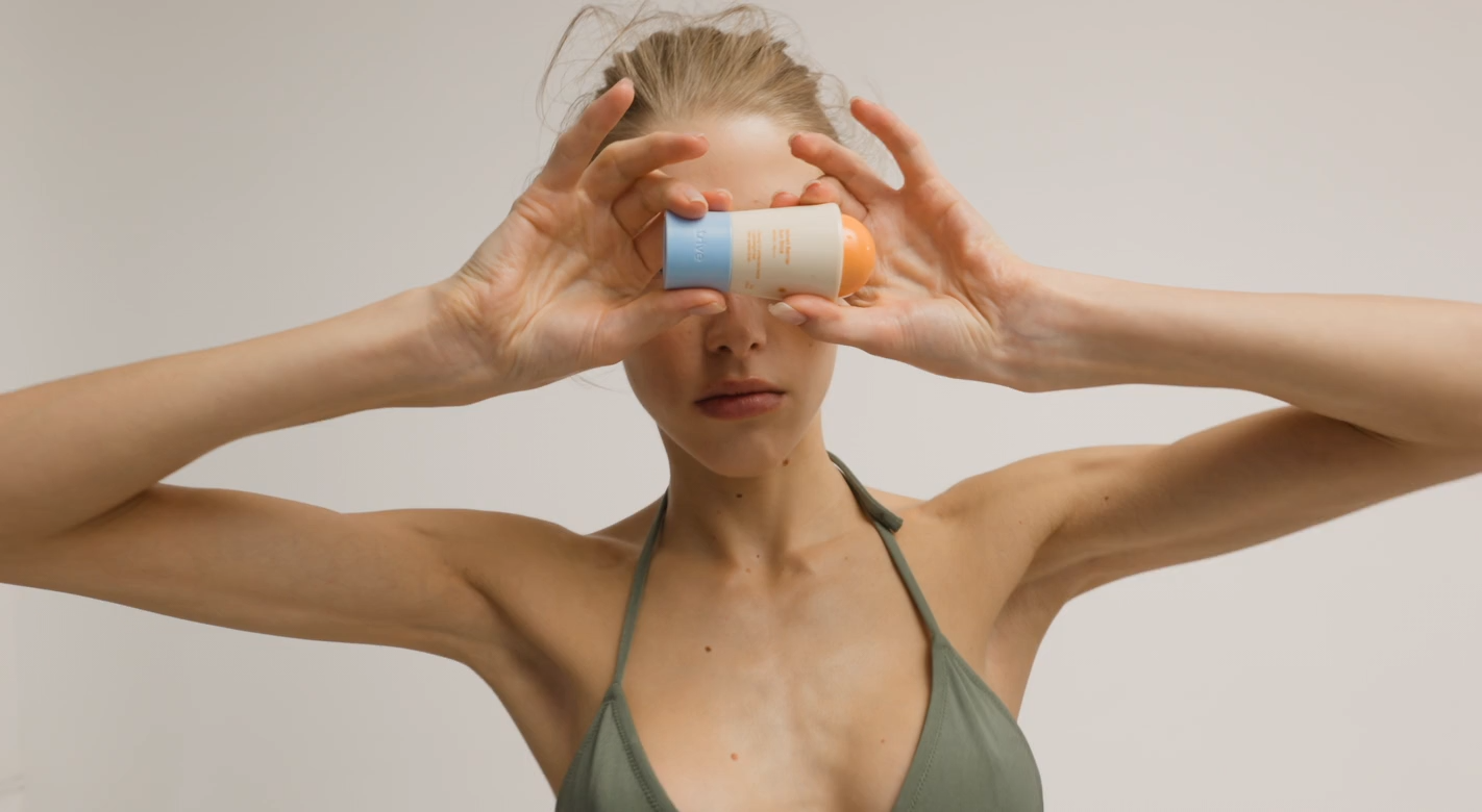 Woman holding a Trive skincare bottle in front of her eyes